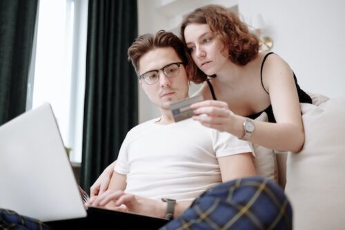 man and woman looking at laptop and credit card